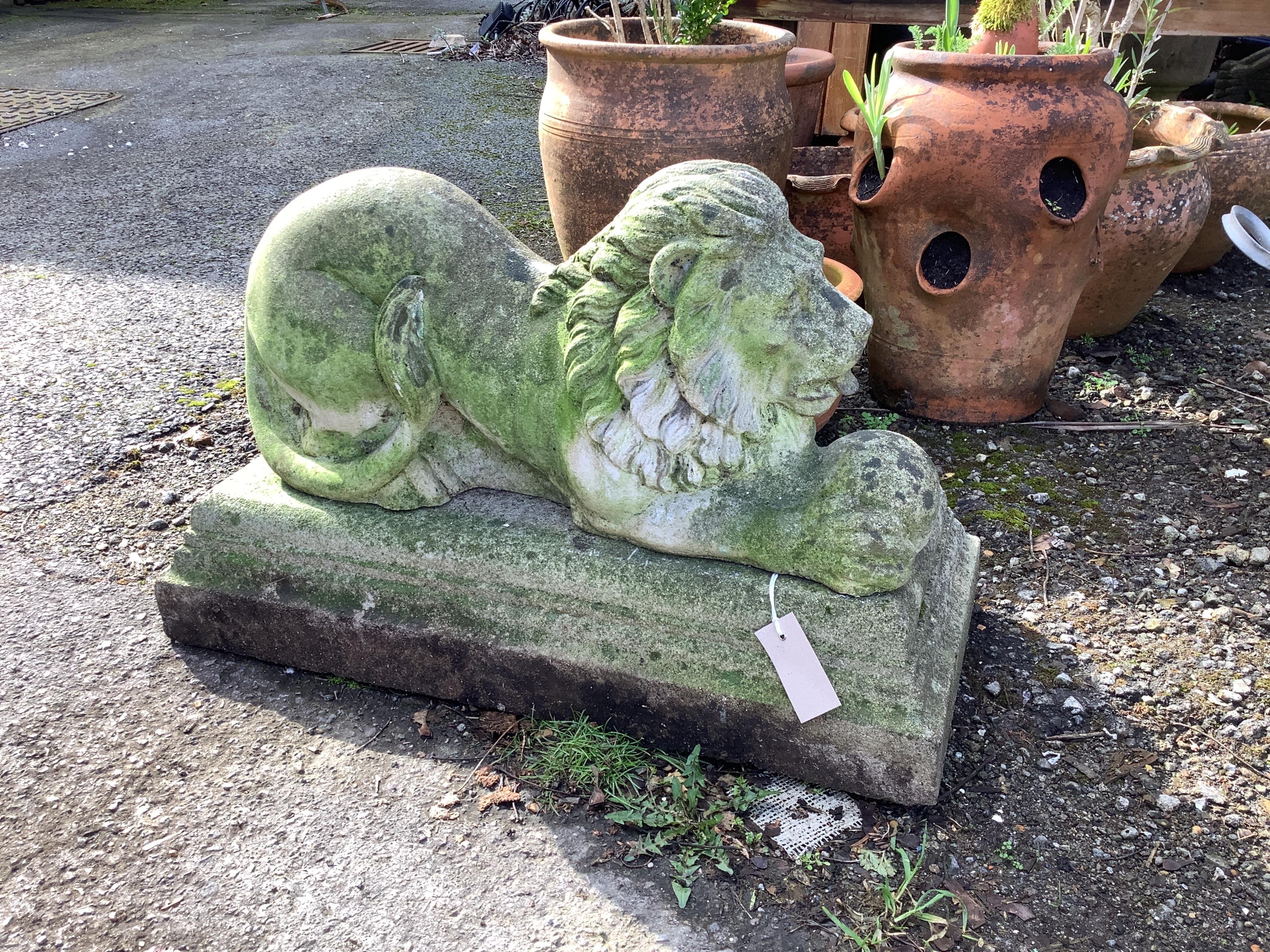 A reconstituted stone recumbent lion garden ornament on base, width 66cm, depth 28cm, height 42cm